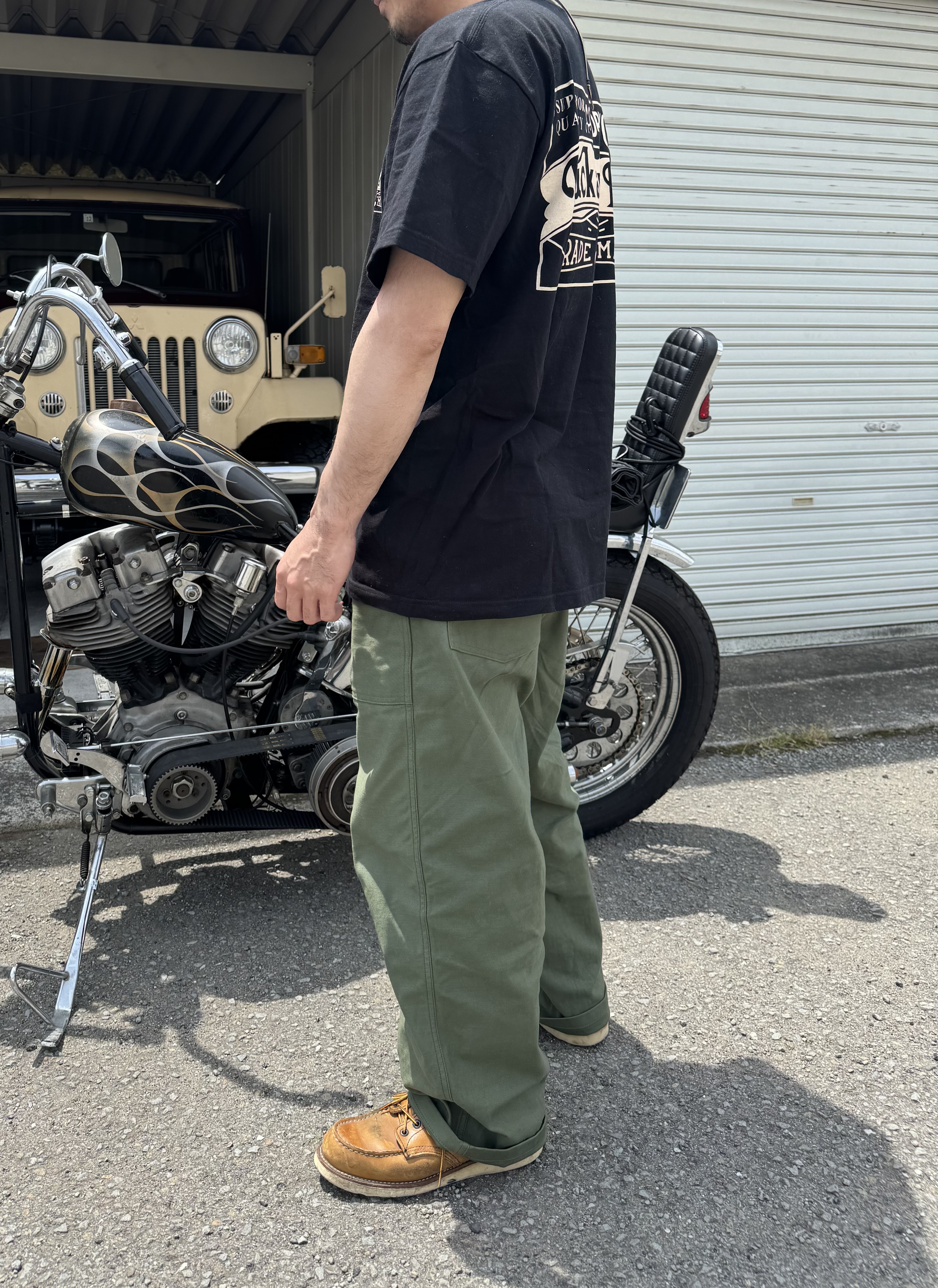 THE REAL McCOY'S ベイカーパンツとレッドウィング、Tシャツを着用したライダーの横向きコーデ写真