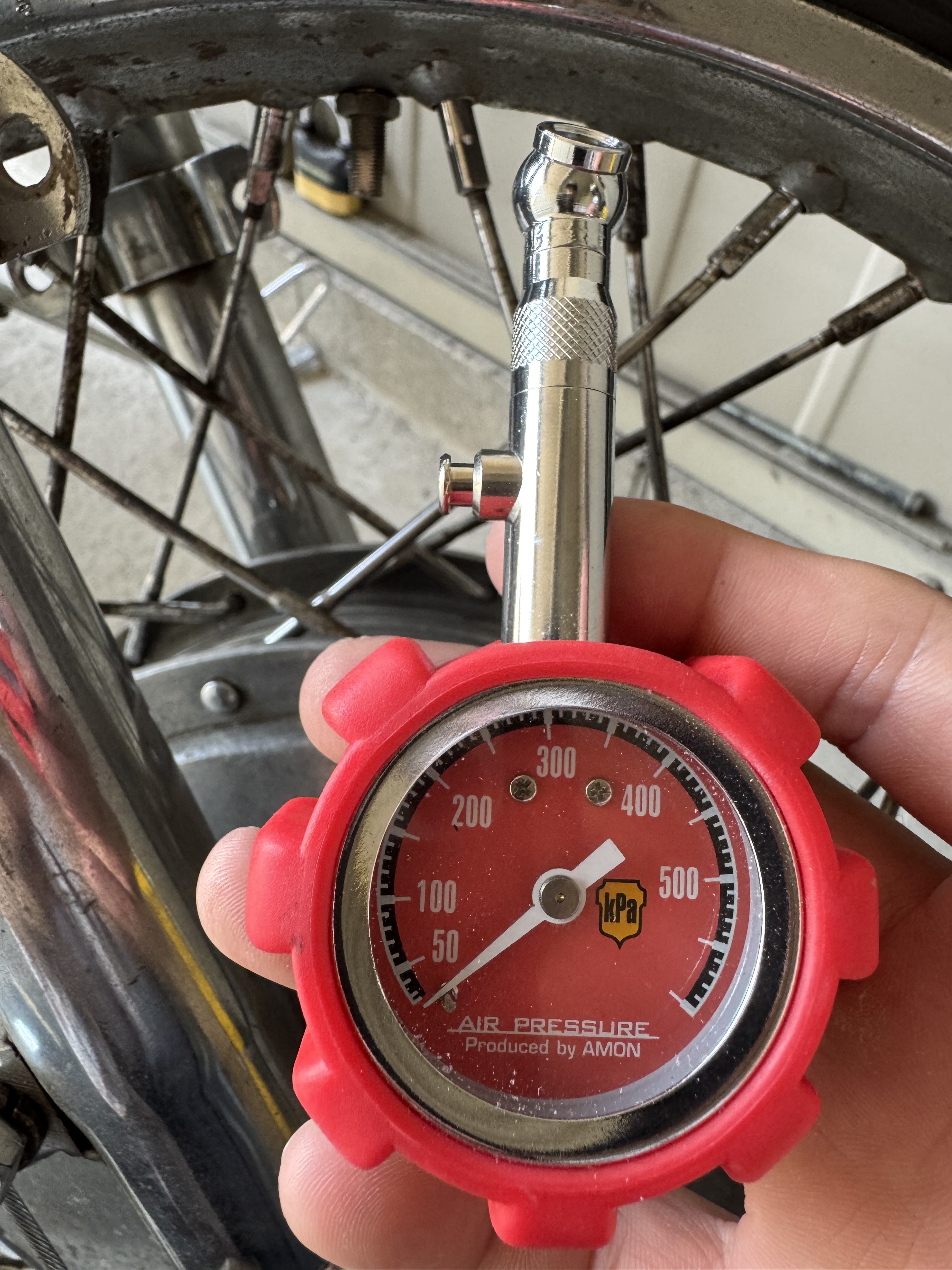 エーモン製エアゲージでバイクタイヤの空気圧を正確に測定している様子