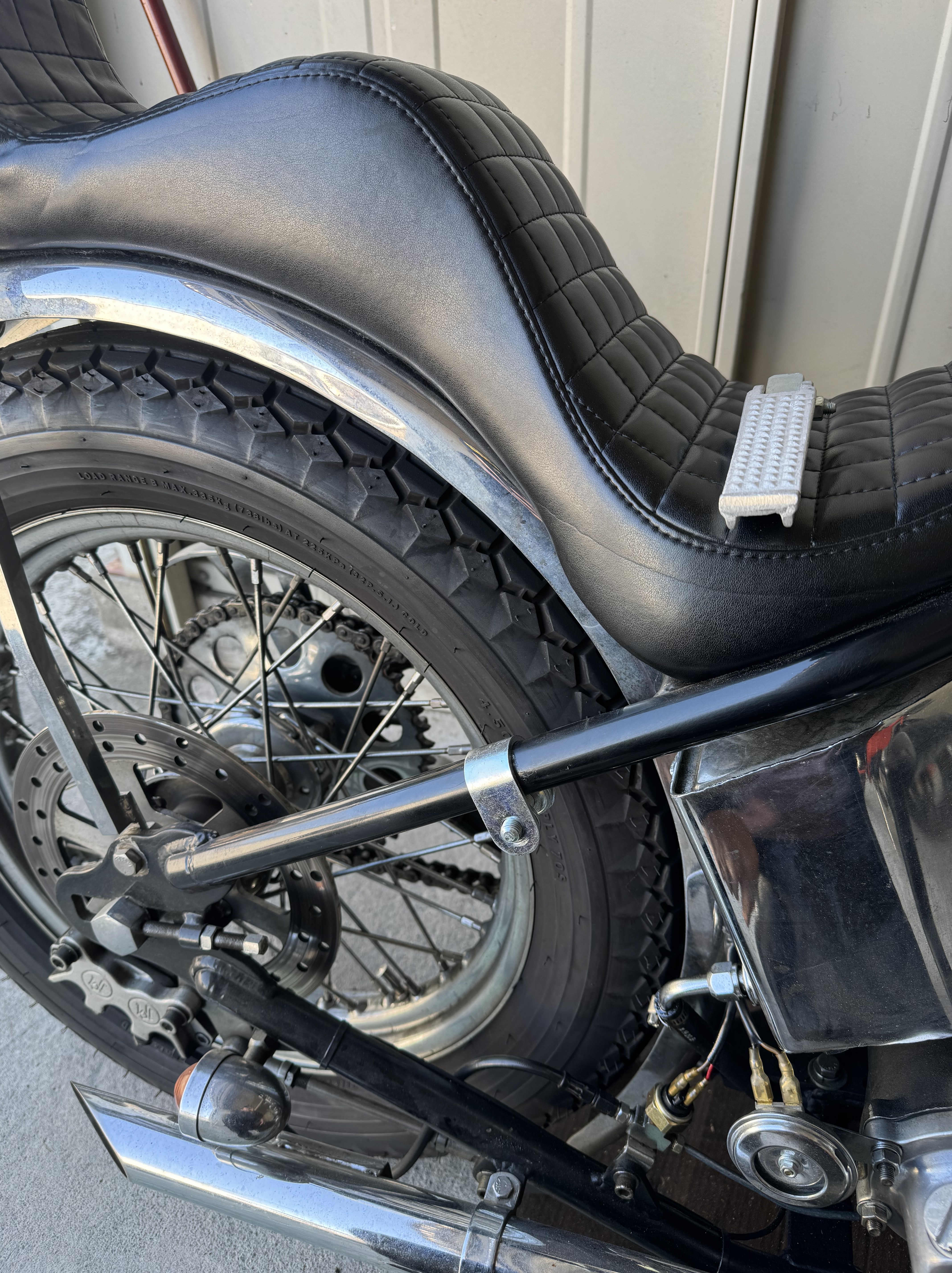 ショベルヘッドのリジッドフレーム左側に仮組みしたクランプステーと、シートに置かれたアンダーソンタイプのアルミステップ