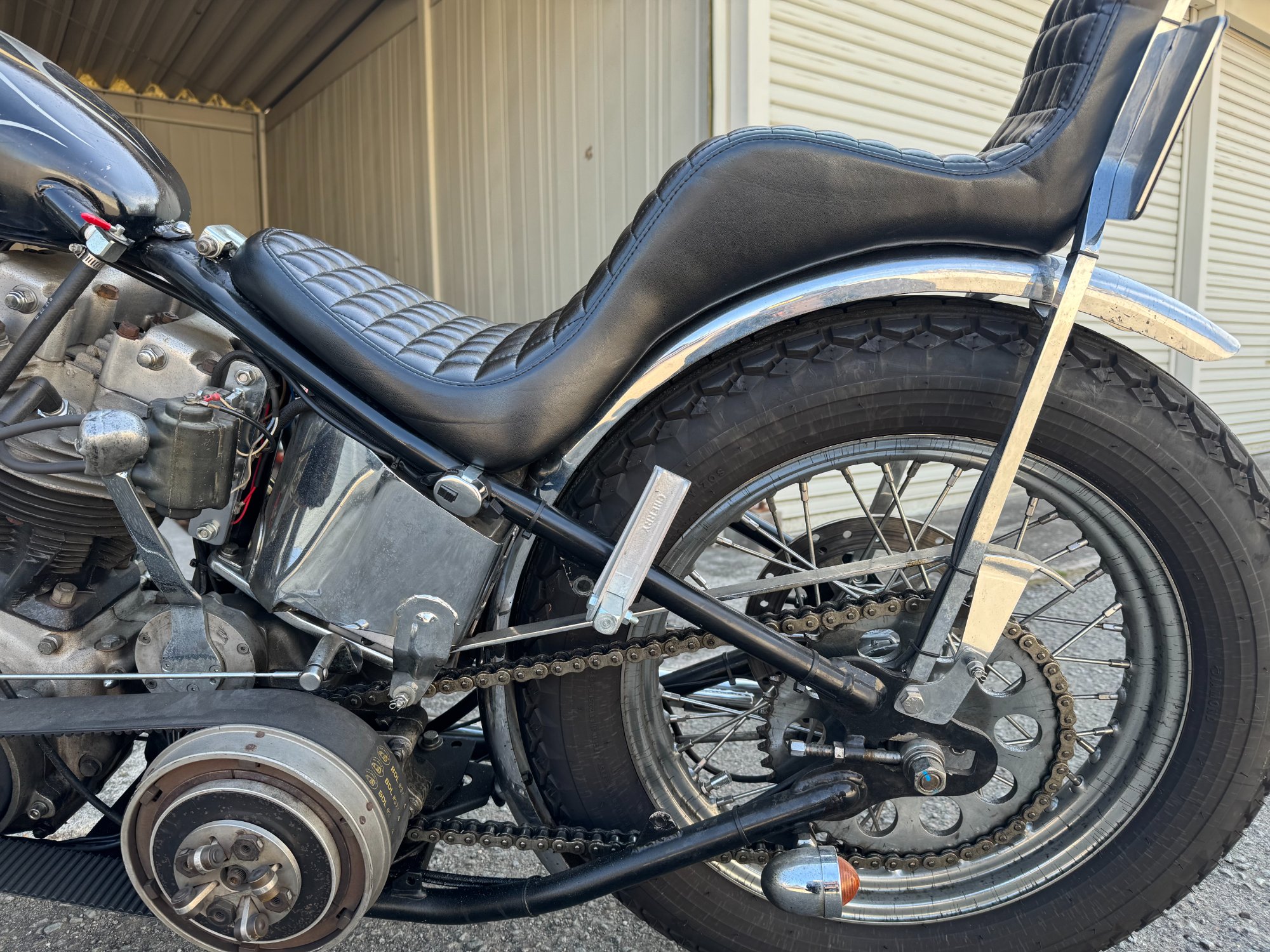 ショベルヘッド・チョッパーの左側リア周り。オープンプライマリー後方のリジッドフレームに沿って折りたたまれたCherry刻印入りアルミステップ。