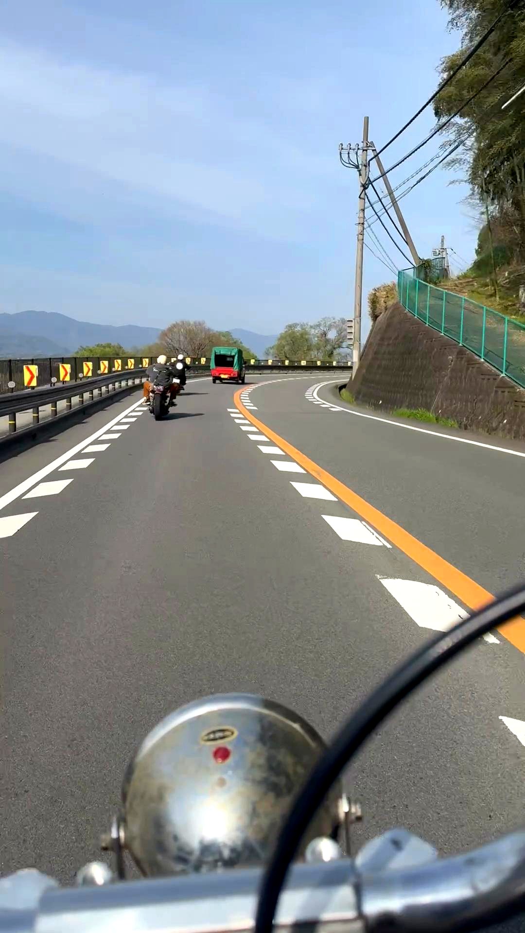 ショベルヘッドチョッパーのツーリング走行中POV ヘッドライト越しの春の道